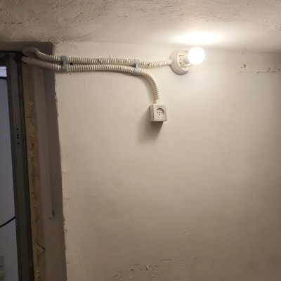 מנורה דולקת, שקע חשמל, צינור חשמל על קיר