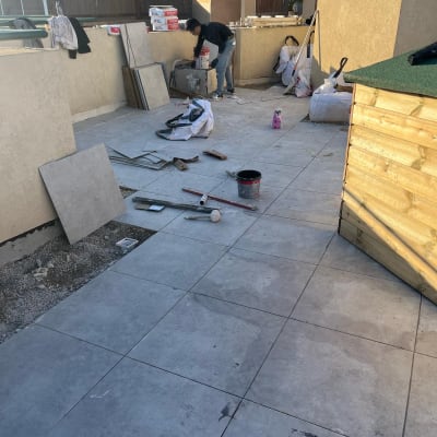 אדם עובד על ריצוף עם כלים וחומרים לאיטום