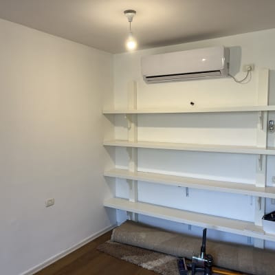 קיר לבן עם מדפים, מזגן ותאורה