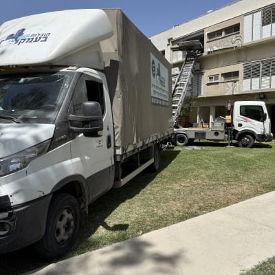 משאית הובלה עם מנוף ליד בניין מגורים