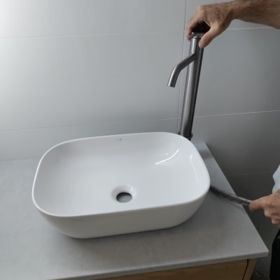 יד מתקינה ברז בכיור אמבטיה לבן