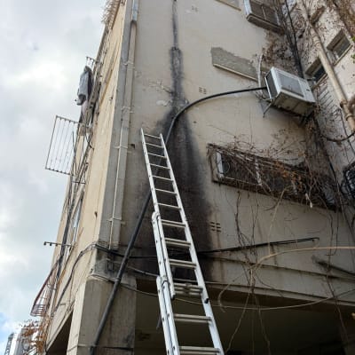 סולם מוצב ליד בניין עם סימני נזק חיצוניים