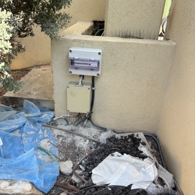 תמונה של קיר עם לוח חשמל וחומרים על הקרקע