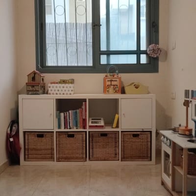 ארון לבן עם קופסאות קש וספרים על מדף