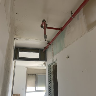 צינור כיבוי אש אדום מותקן על תקרה לבנה