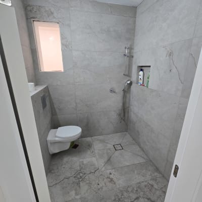 חדר אמבטיה עם אריחים חדשים, מקלחון ואסלה מותקנים