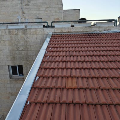 גג רעפים חומים עם מסגרת מתכת אפורה