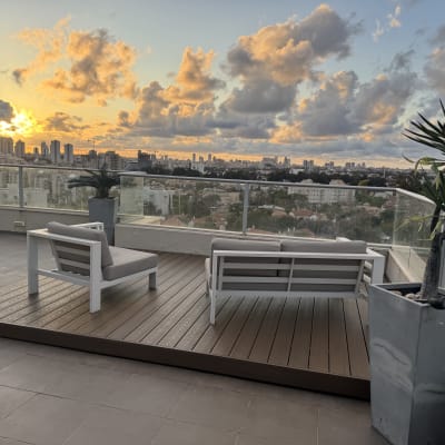 שתי כורסאות על דק עץ במרפסת עם צמחייה