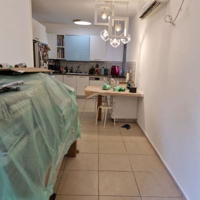 מטבח עם כיסוי פלסטיק על רהיטים, מנורות תלויות, ומזגן על הקיר