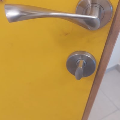 ידית דלת מתכתית על דלת צהובה