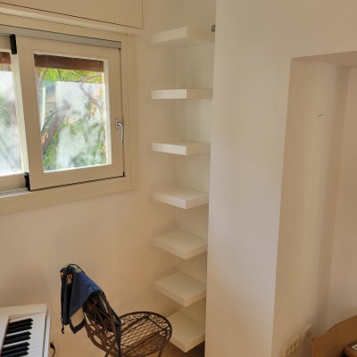 מדפי קיר לבנים מותקנים בפינה ליד חלון