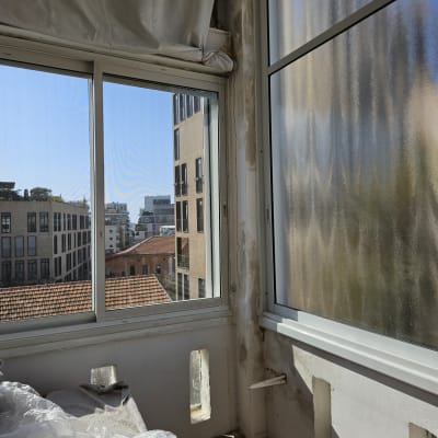 תריסים לבנים על חלון זכוכית עם נוף עירוני