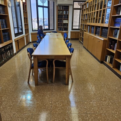 חדר ספרייה עם שולחן וכיסאות, מדפים מלאים בספרים