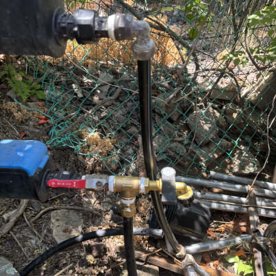 צנרת ומחברים בגינה עם צמחייה ברקע