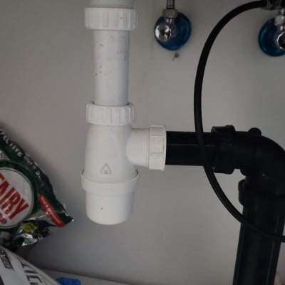 צנרת מתחת לכיור עם חיבורים לבנים ושחורים