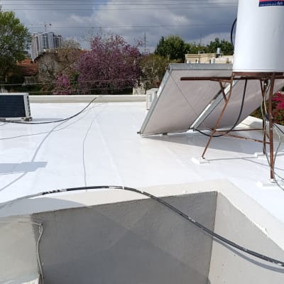 גג אטום בלבן עם קולטי שמש ומזגנים