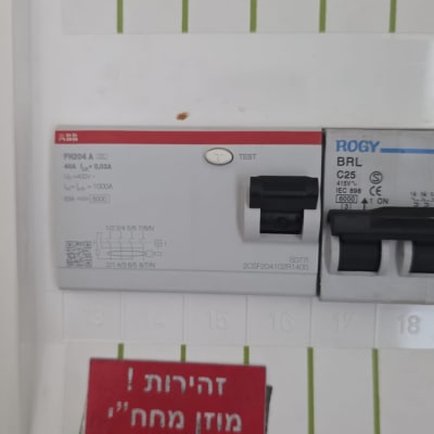 תקריב של מפסק פחת ומאמ"ת תלת-פאזי בלוח חשמל