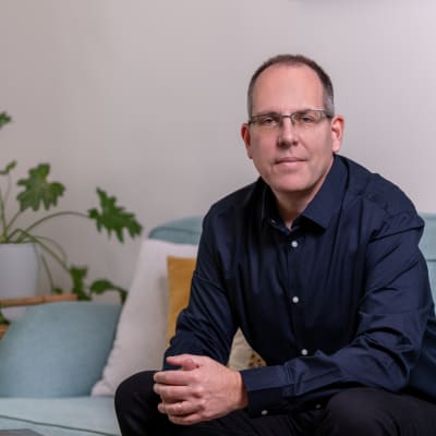 אדם יושב על ספה עם צמח ברקע