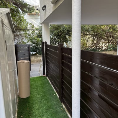 גדר צבועה בצבע כהה ליד דשא סינתטי