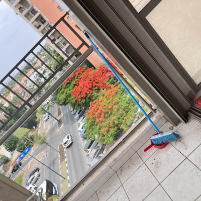 מטאטא כחול ואדום ודלי עם סמרטוט אדום על רצפה מלוכלכת