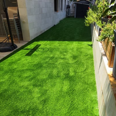 דשא סינטטי בחצר עם צמחים ירוקים בצד