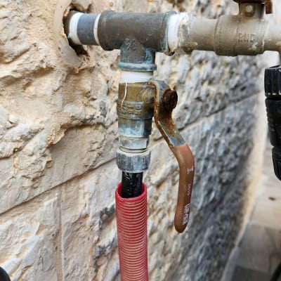 ברז מתכת עם ידית חלודה וצינור אדום