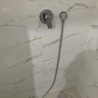 ברז ומקלחת בחדר אמבטיה עם אריחים לבנים