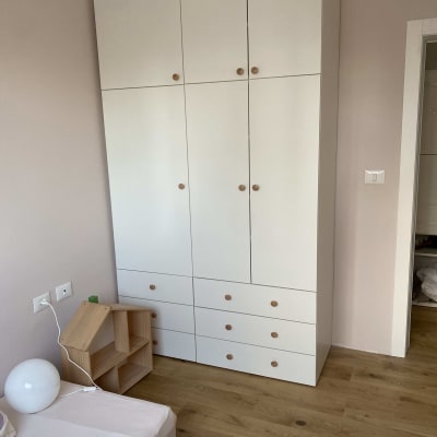 ארון בגדים לבן עם ידיות עץ בחדר שינה
