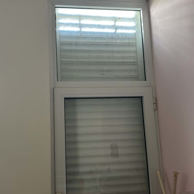 תריסים סגורים על חלון זכוכית עם מסגרת לבנה