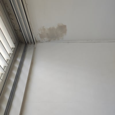 כתם רטיבות בתקרה ליד חלון עם תריסים