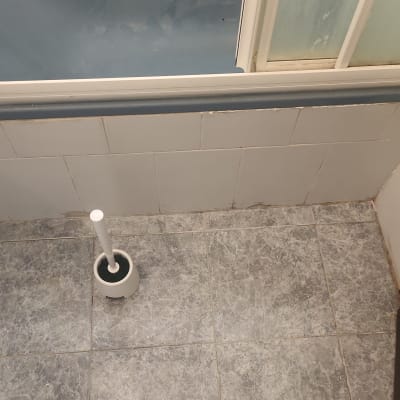 מקלחת עם רצפת אריחים ומברשת אסלה