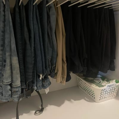 מכנסיים תלויים על קולבים וסל כביסה לבן