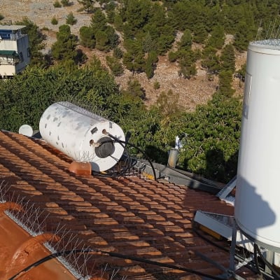 דוד שמש ומיכל מים על גג רעפים עם דוקרנים