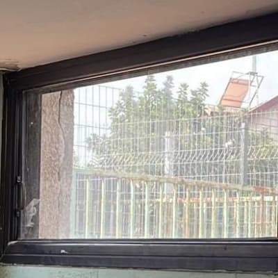 חלון זכוכית עם מסגרת מתכתית, נוף חיצוני מטושטש