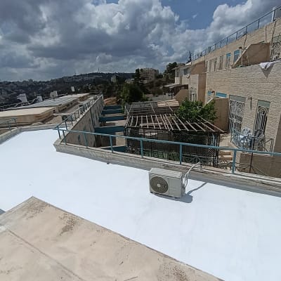 גג אטום עם נוף של בניינים ושמיים מעוננים