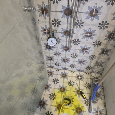מד לחץ מים על רצפת מקלחת עם אריחים צבעוניים