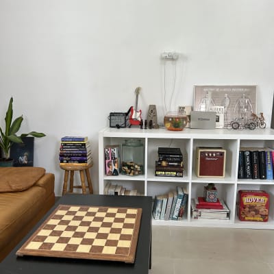 מדף לבן עם ספרים, קופסאות ותמונות, לוח שחמט על שולחן שחור