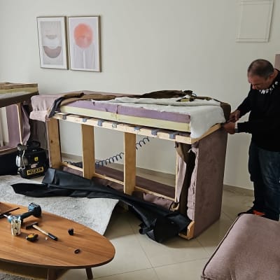 אדם מרפד ספה עם כלים וחומרים על שולחן