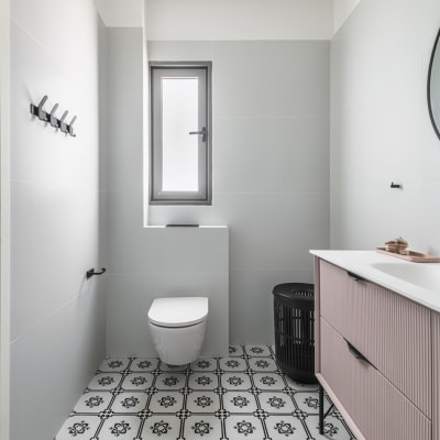 חדר אמבטיה עם אריחים מעוצבים, כיור וארון ורוד