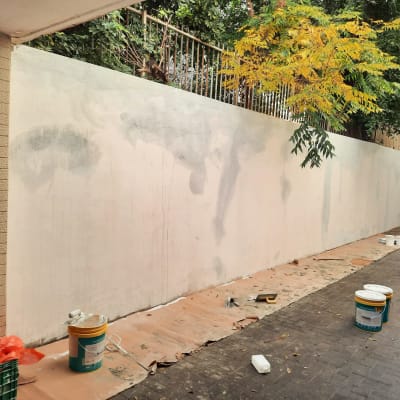 קיר צבוע חלקית עם דליי צבע וכלי עבודה