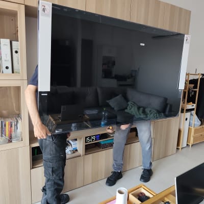 שני אנשים מתקינים טלוויזיה גדולה בסלון