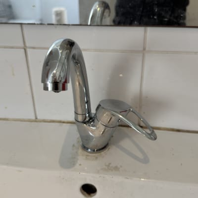 ברז כרום על כיור לבן עם כתמים