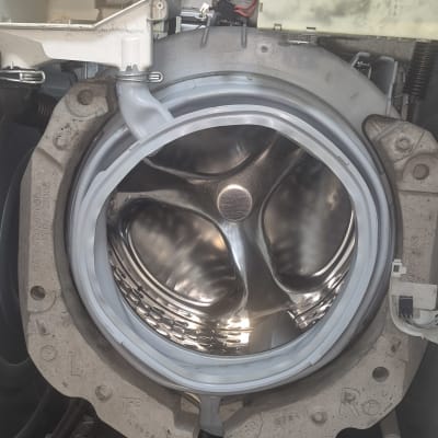 תוף מכונת כביסה פתוח עם חלקים פנימיים חשופים