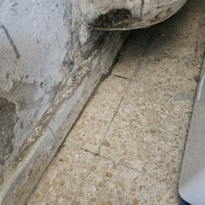 קיר עם סימני רטיבות ונזילה על הרצפה