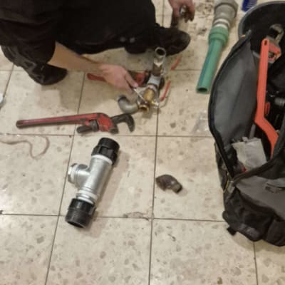 אדם עובד על צנרת עם כלים על רצפה