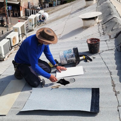 אדם עובד על תיקון גג עם כלים וחומרים