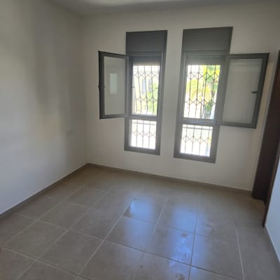 חדר ריק עם חלונות פתוחים ורצפת אריחים