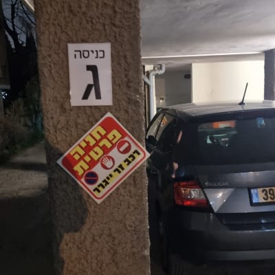 עמוד בטון עם שלט חניה פרטית, רכב חונה לידו.