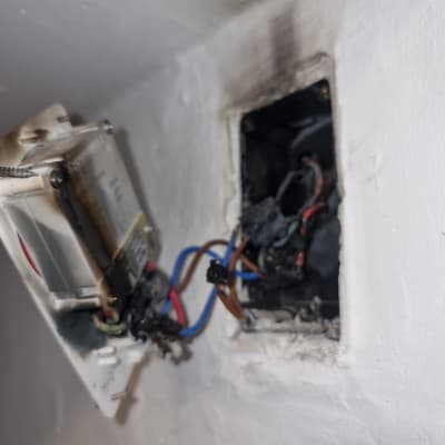 חוטי חשמל חשופים בקיר עם שקע פתוח