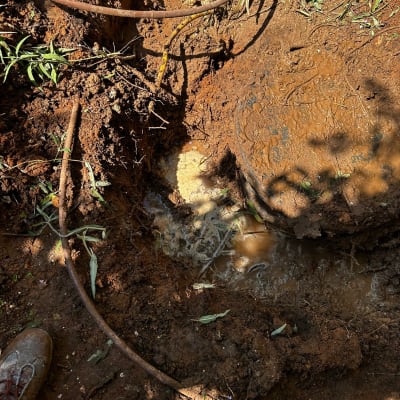 צינור מים שבור באדמה בוצית עם נזילה
